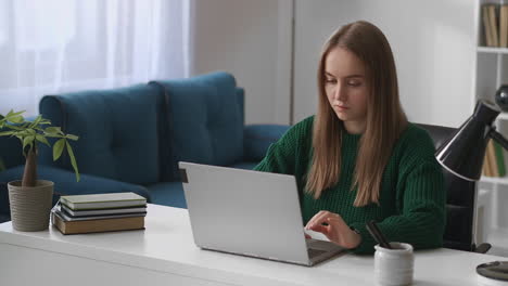 female-student-is-using-laptop-at-home-for-e-learning-distance-online-education-young-woman-is-working-with-notebook-sitting-at-table-in-room